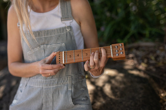 Hands practicing a chord shape on a Chordly silent guitar chord trainer with real strings